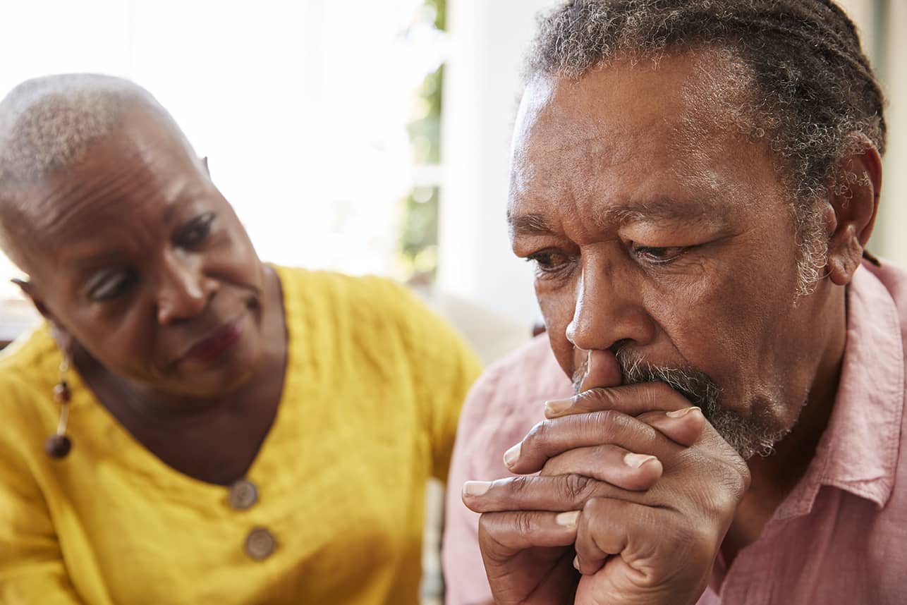 Older woman trying to console her husband who is struggling with anticipatory grief.